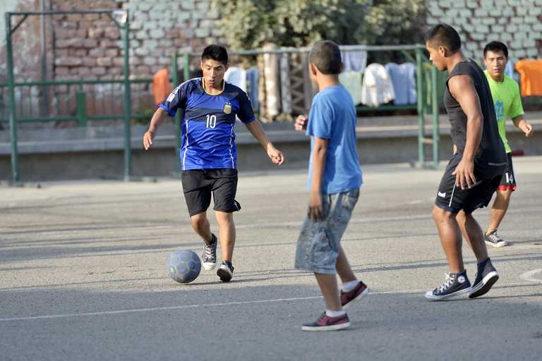 Drei Jungen spielen Fußball auf Asphalt