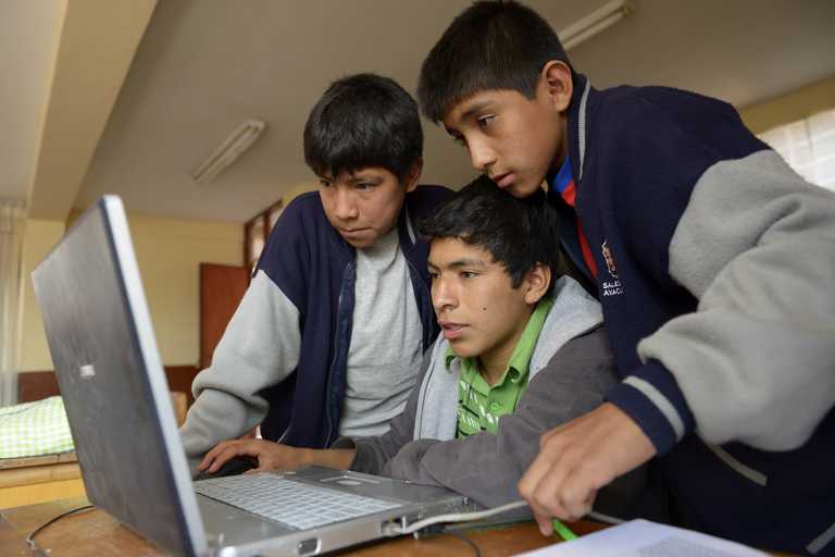 Drei Junge schauen auf einen Laptop
