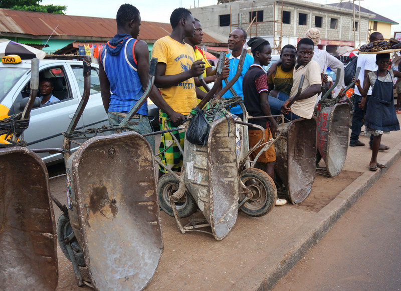 Jugendliche warten am Straßenrand mit Schubkarren