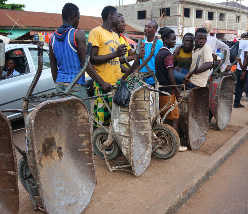 Jugendliche warten am Straßenrand mit Schubkarren