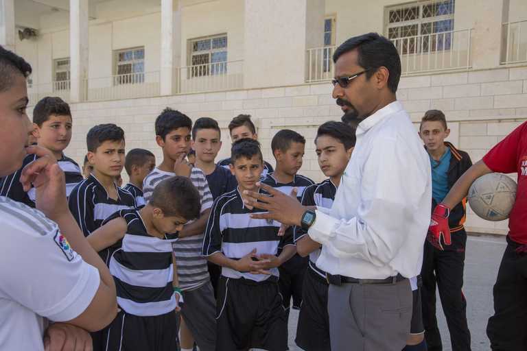 Pater Raj spricht mit einer Gruppe Jungen im Fußballtrikot