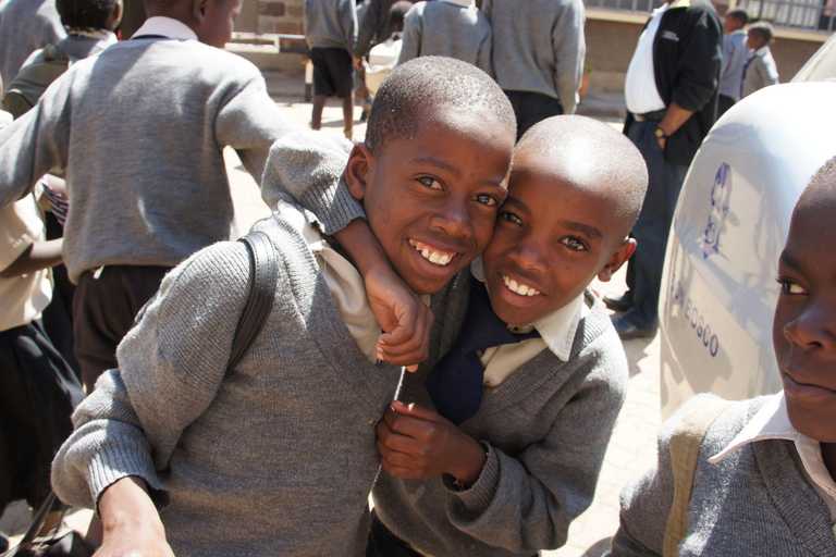Zwei Jungen in Schuluniform, die sich umarmen