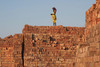 Kind steht auf einer Mauer aus Ziegeln in einer Ziegelfabrik