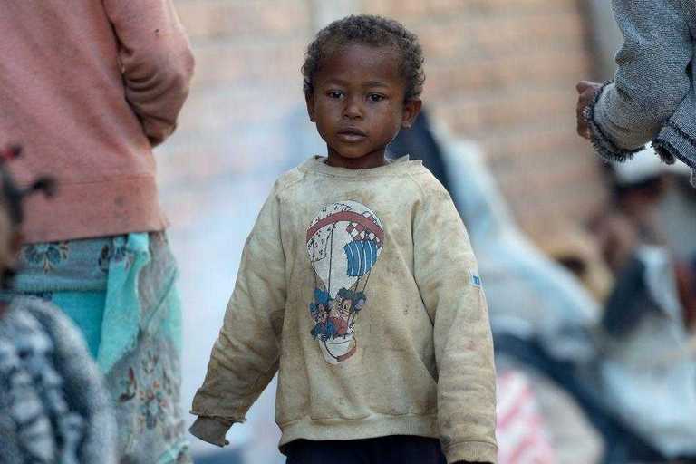 Ein kleiner Junge in verschlissener Kleidung auf der Straße