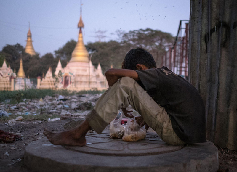 Ein Junge kauert auf dem Boden vor einer goldenen Pagode