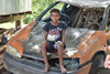 Junge sitzt auf Auto Wrack