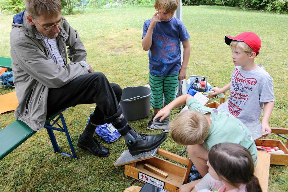 Kinder putzen einem Mann die Schuhe