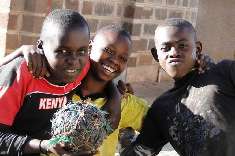 Drei Jungen mit einem zerfledderten Fußball