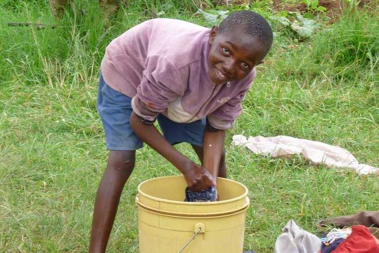 Ein Junge wäscht Kleidung in einem Eimer