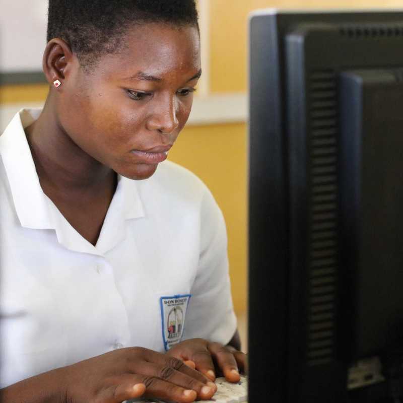 Mädchen sitzt hinter einem Computer-Bildschirm