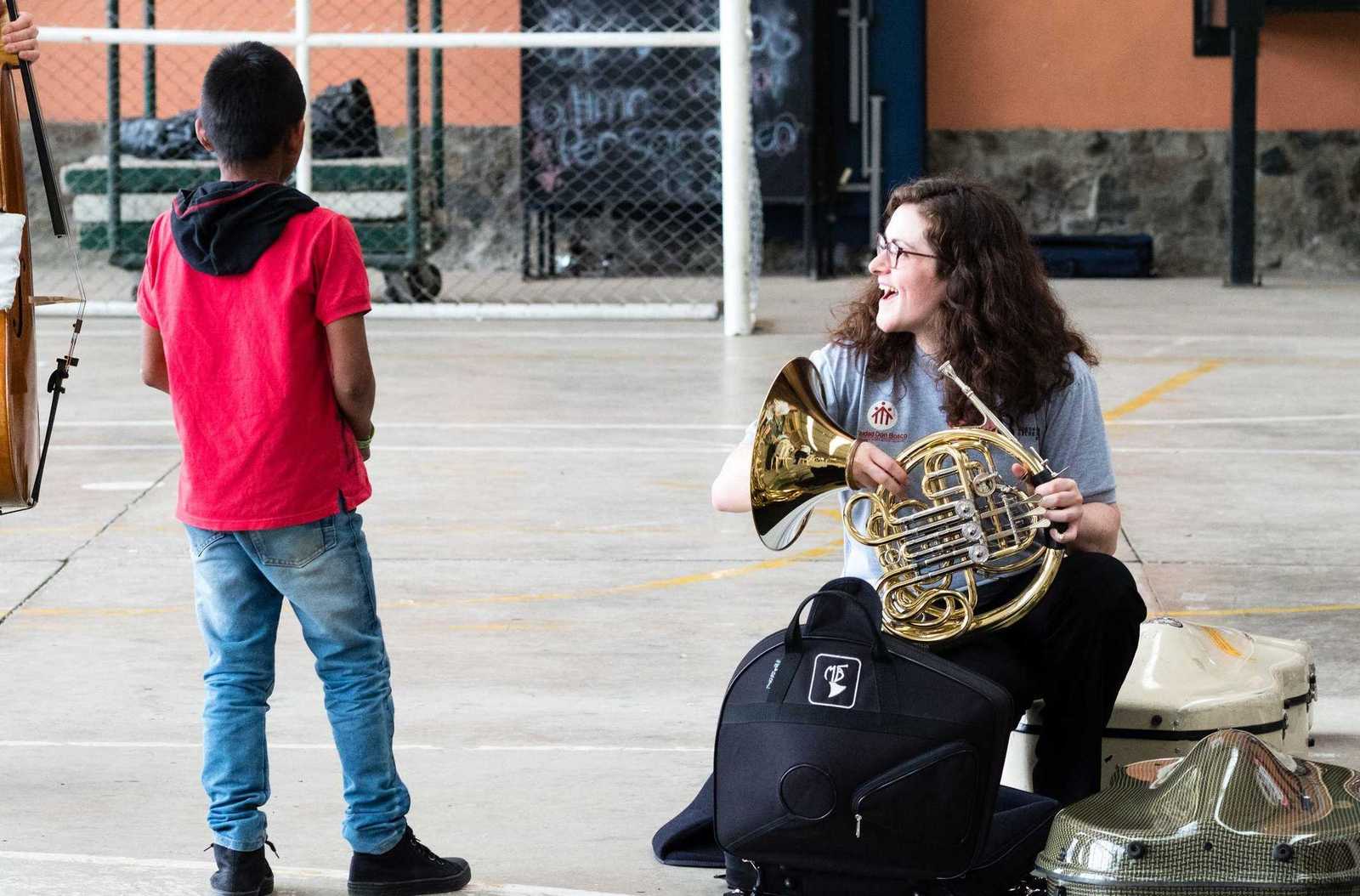 Musikerin des Beethoven Orchester zeigt einem jungen wie man Horn spielt