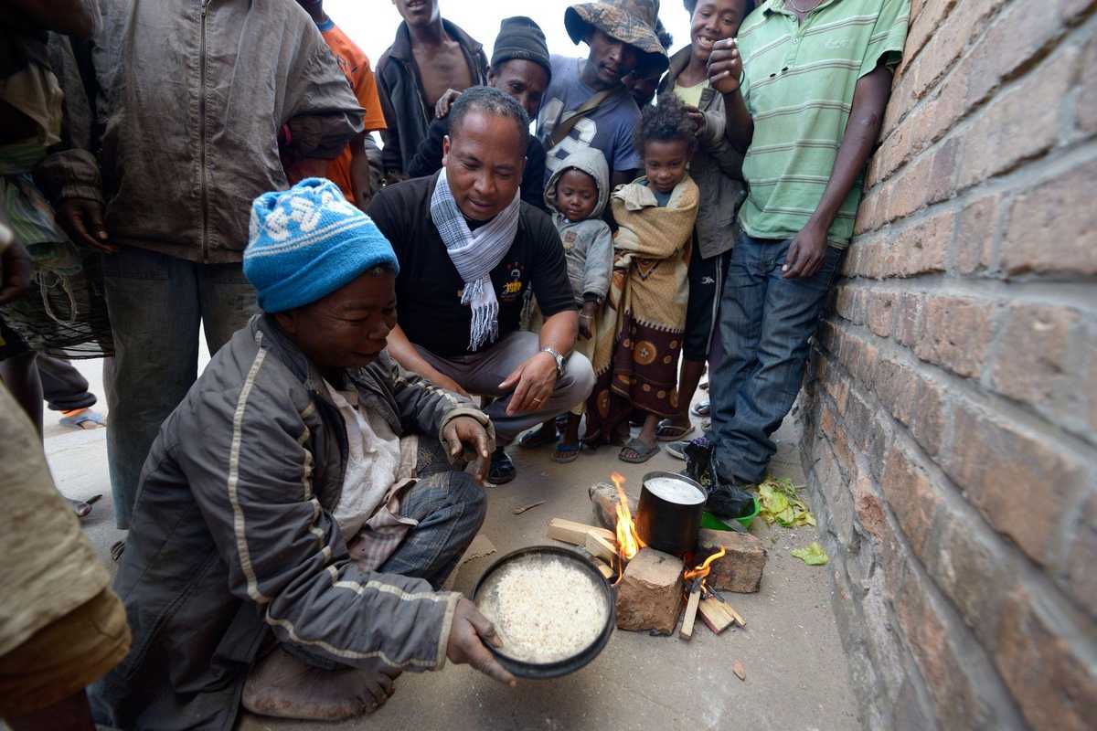 Ein Junge zeigt Pater Jannot, wie er sich auf der Straße etwas zu essen macht