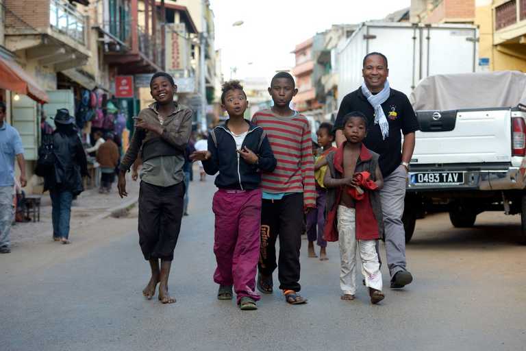 Pater Jannot und lachende Kinder ziehen durch die Straße